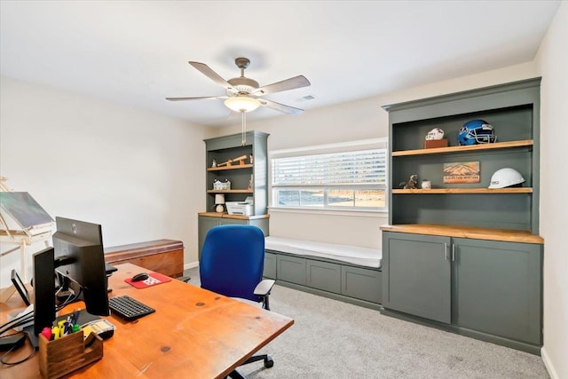 carpeted office space featuring baseboards, visible vents, and a ceiling fan