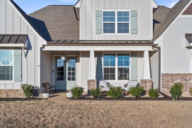 view of front of property featuring board and batten siding, a standing seam roof, roof with shingles, and metal roof