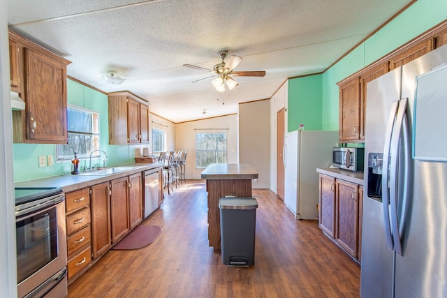 kitchen with a kitchen island, stainless steel appliances, crown molding, under cabinet range hood, and a sink