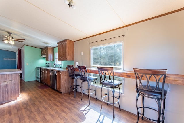 kitchen featuring brown cabinets, light countertops, appliances with stainless steel finishes, dark wood-type flooring, and a sink