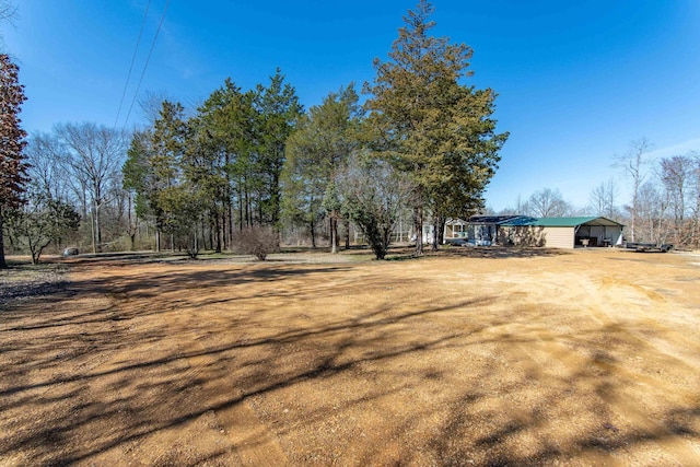 view of yard with dirt driveway and a detached carport