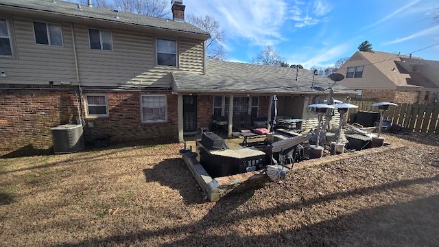 back of property featuring a chimney, fence, cooling unit, and brick siding