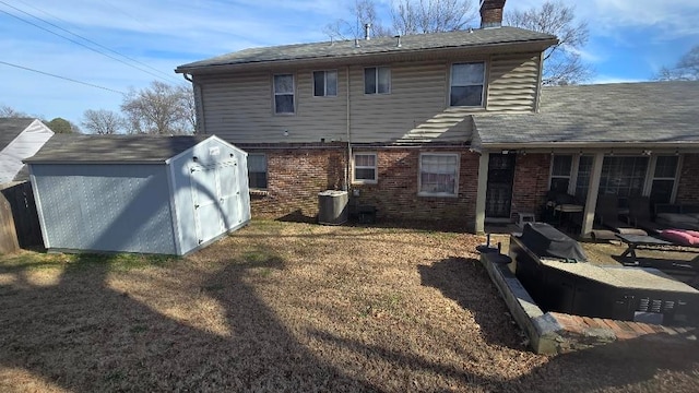 back of property with an outbuilding, brick siding, a chimney, central air condition unit, and a shed