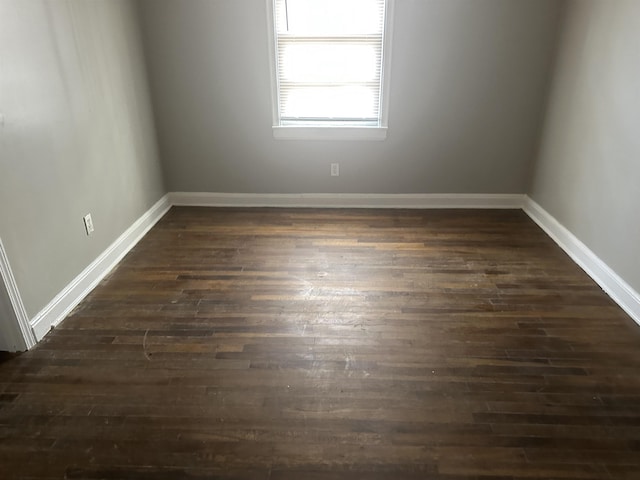 empty room featuring baseboards and dark wood-type flooring