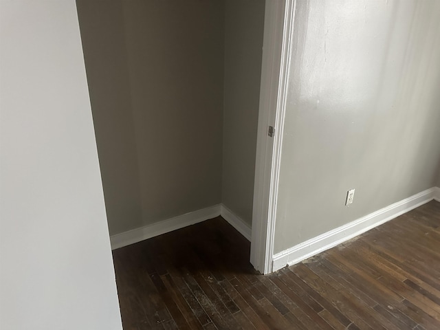 empty room featuring baseboards and dark wood finished floors