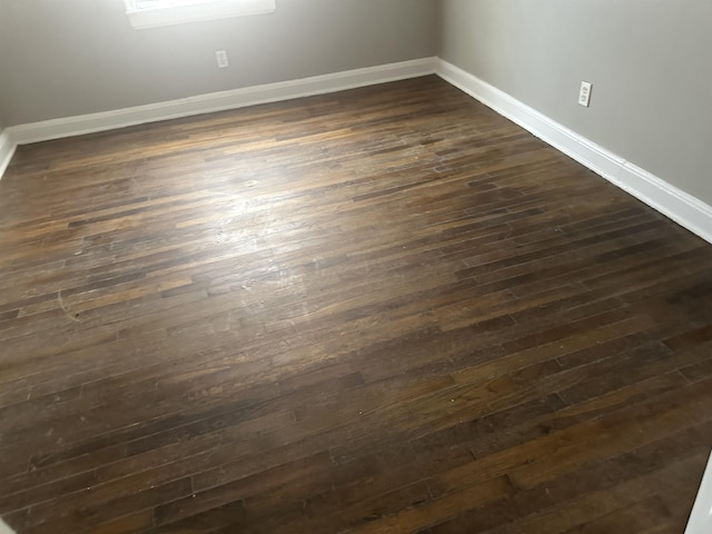 empty room featuring dark wood-type flooring and baseboards