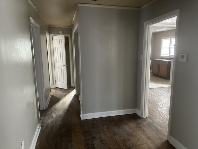 hallway featuring ornamental molding, dark wood-style flooring, and baseboards