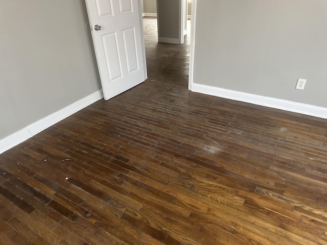 empty room featuring dark wood-style flooring and baseboards