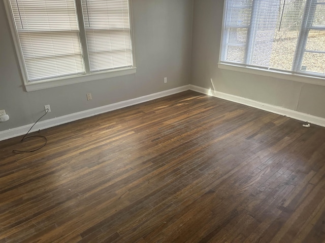 spare room featuring dark wood-style floors and baseboards