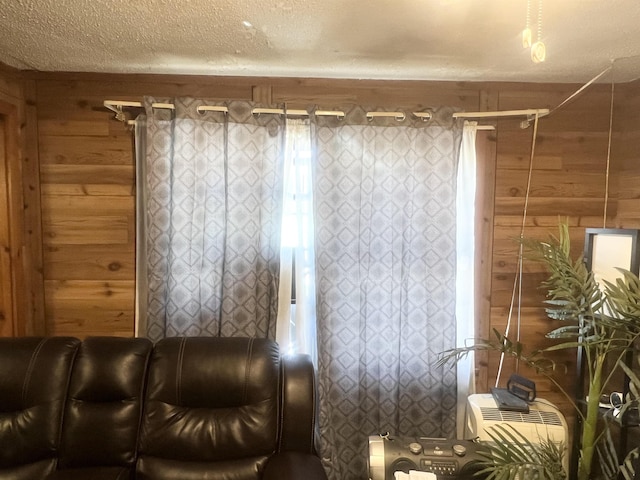 unfurnished living room with a textured ceiling and wood walls