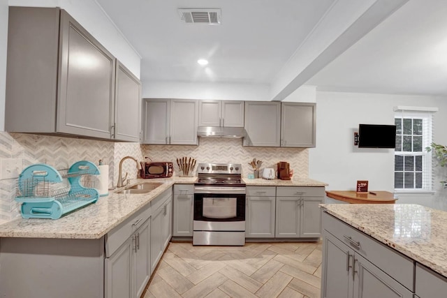 kitchen with visible vents, gray cabinetry, stainless steel range with electric cooktop, a sink, and under cabinet range hood