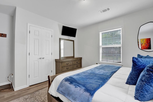 bedroom with wood finished floors, visible vents, and baseboards