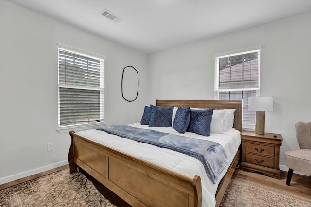 bedroom featuring wood finished floors, visible vents, and baseboards