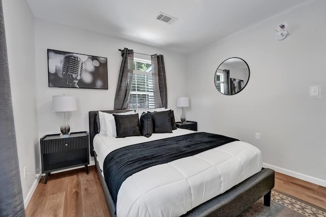 bedroom with wood finished floors, visible vents, and baseboards