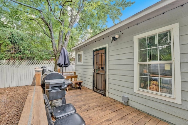 wooden terrace featuring grilling area and fence