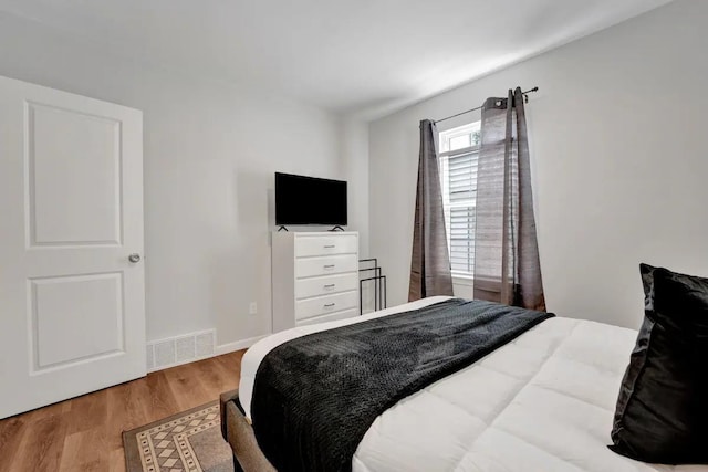 bedroom featuring wood finished floors, visible vents, and baseboards