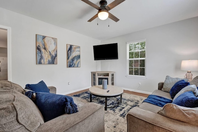 living area featuring wood finished floors, a ceiling fan, and baseboards