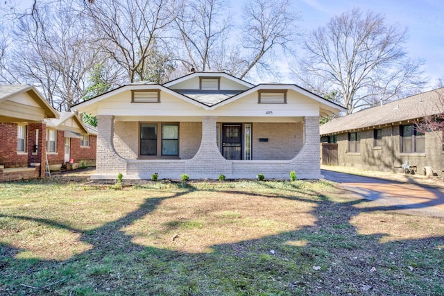 bungalow featuring a front lawn and brick siding