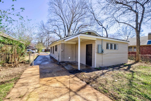 view of side of property featuring concrete driveway, brick siding, and fence