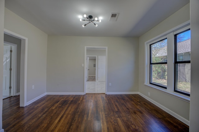 unfurnished room featuring dark wood-style floors, a chandelier, visible vents, and baseboards