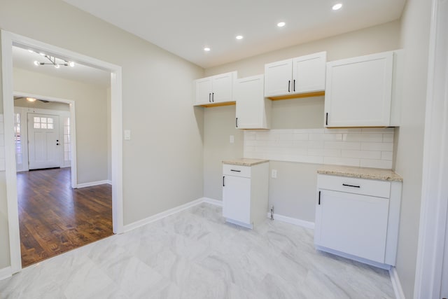 kitchen with baseboards, light stone counters, white cabinets, and decorative backsplash