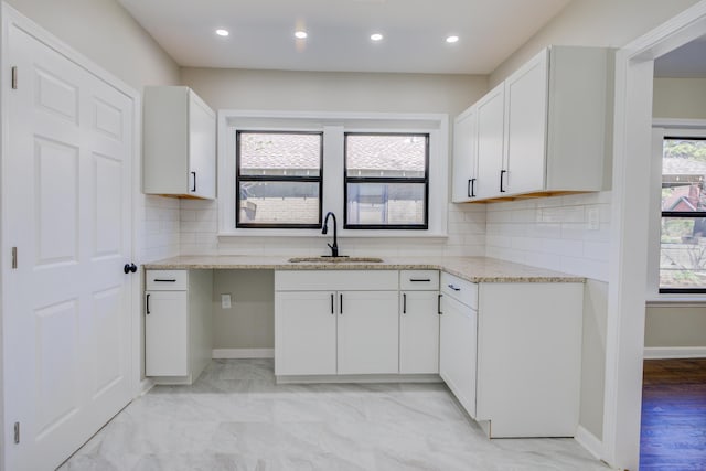 kitchen featuring tasteful backsplash, light stone counters, white cabinetry, a sink, and recessed lighting