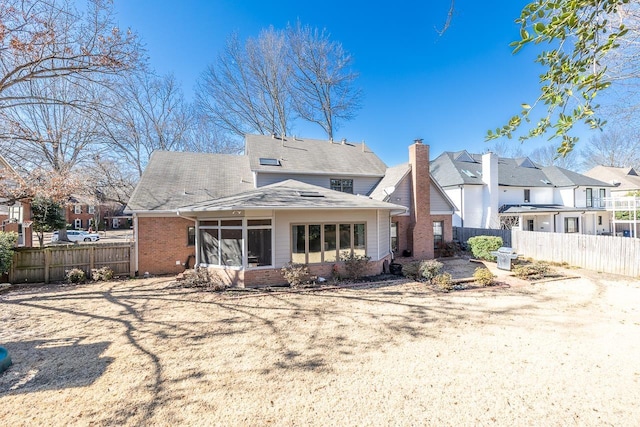 back of property with brick siding, a residential view, fence, and a sunroom