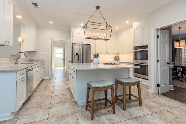 kitchen featuring a center island, stainless steel appliances, visible vents, ornamental molding, and a sink