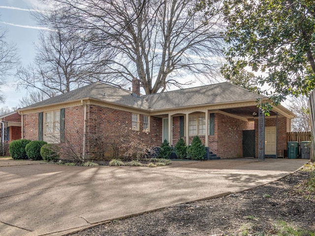 ranch-style home with brick siding, driveway, a chimney, and fence