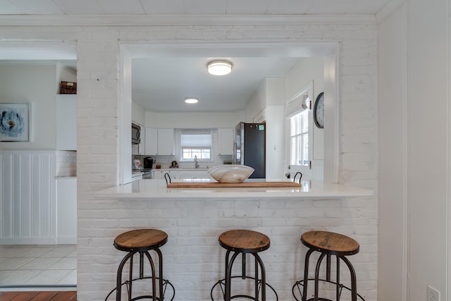 kitchen with a breakfast bar, stainless steel appliances, a sink, and light countertops