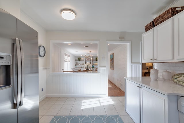 kitchen with white cabinets, wainscoting, stainless steel refrigerator with ice dispenser, and light tile patterned floors