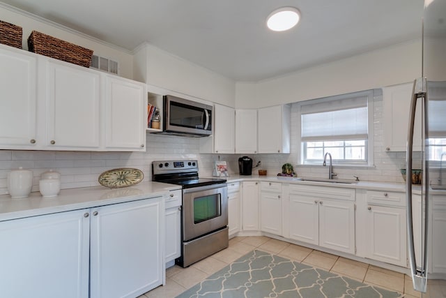 kitchen with light tile patterned floors, decorative backsplash, appliances with stainless steel finishes, white cabinetry, and a sink