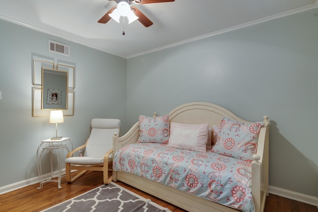 bedroom with baseboards, visible vents, ceiling fan, wood finished floors, and crown molding