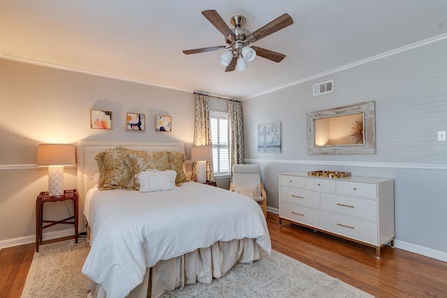 bedroom with baseboards, visible vents, ceiling fan, ornamental molding, and wood finished floors