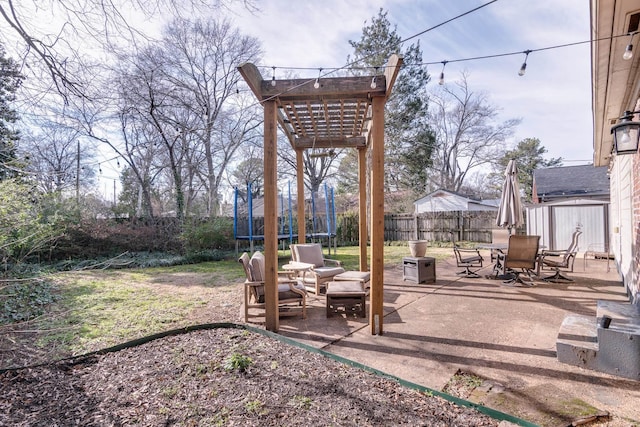 view of yard with a patio, outdoor dining area, an outdoor structure, fence, and a trampoline