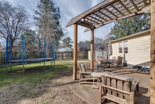 view of yard with a trampoline, an outbuilding, a storage shed, fence, and a pergola