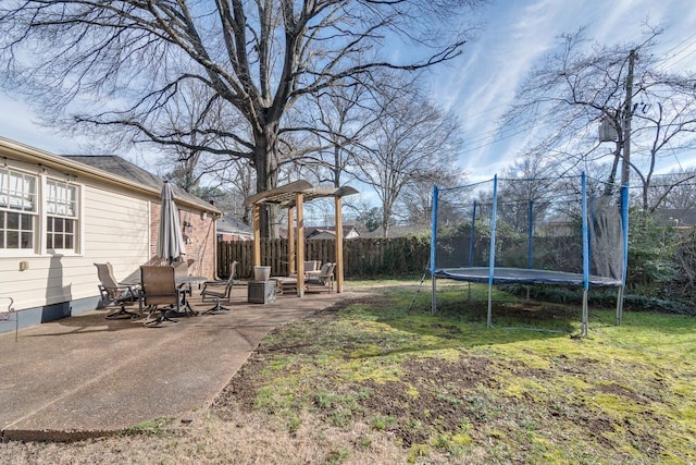 view of yard featuring a patio, a trampoline, and fence