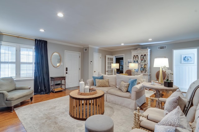 living area with recessed lighting, visible vents, wood finished floors, and ornamental molding