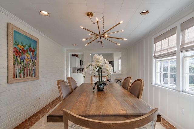 dining space featuring brick wall, crown molding, a notable chandelier, and recessed lighting