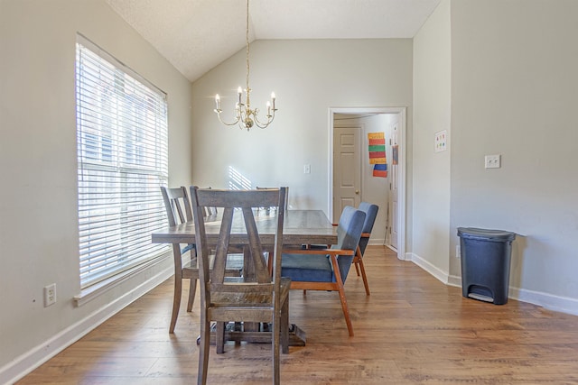 dining space with vaulted ceiling, baseboards, wood finished floors, and an inviting chandelier