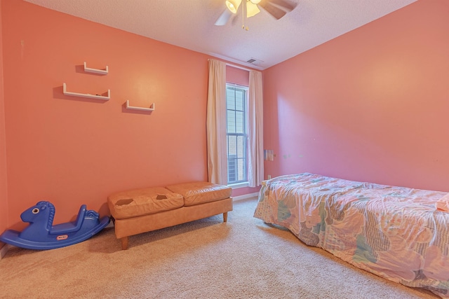 carpeted bedroom featuring ceiling fan, visible vents, and a textured ceiling