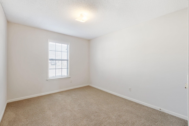 carpeted empty room featuring a textured ceiling and baseboards