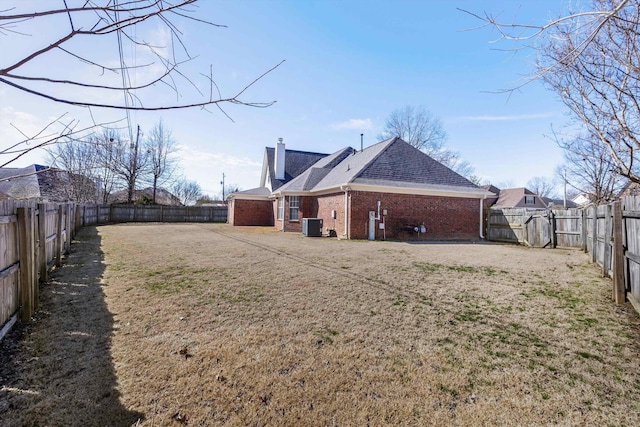 back of property featuring central AC, brick siding, a chimney, and a fenced backyard