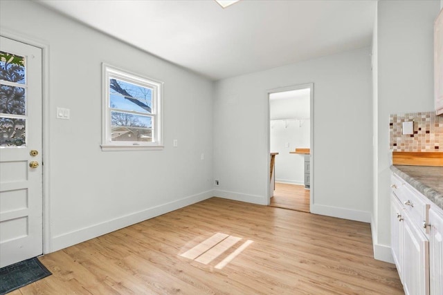 unfurnished dining area with light wood-style floors and baseboards