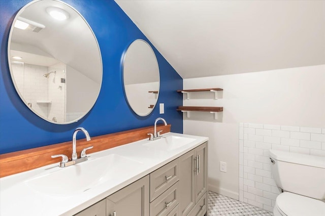 bathroom with toilet, double vanity, vaulted ceiling, and a sink