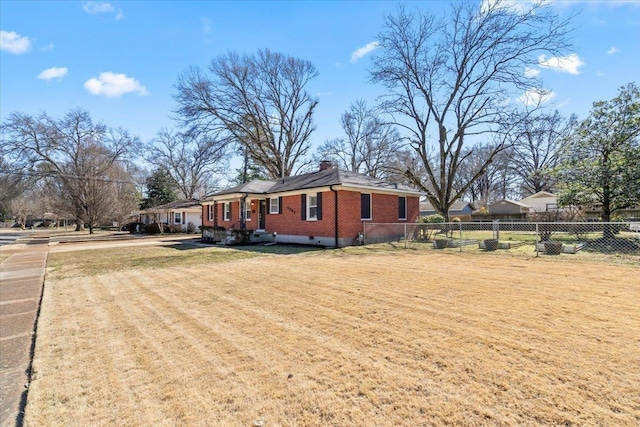 view of property exterior with a yard, brick siding, a chimney, and fence