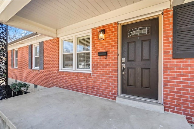 entrance to property with crawl space, covered porch, and brick siding