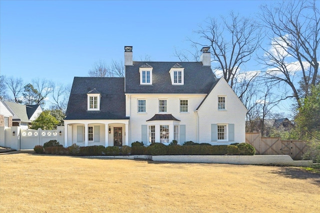 view of front of house featuring a chimney, a front yard, fence, and a gate