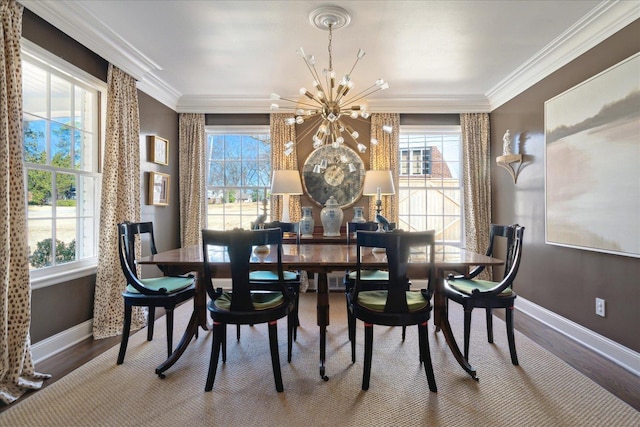 dining space featuring baseboards, ornamental molding, wood finished floors, and a notable chandelier