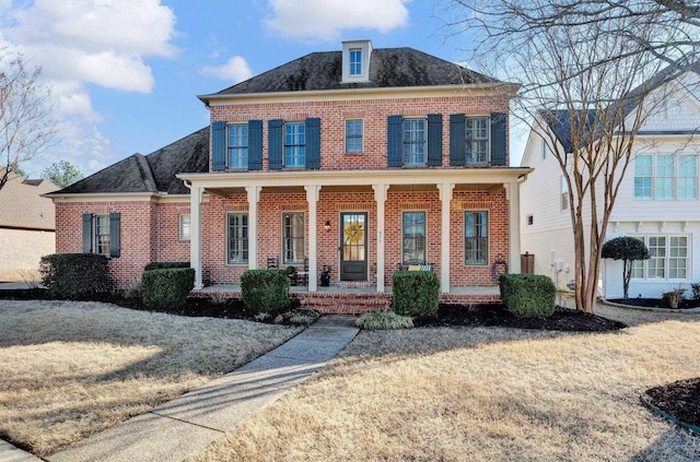 view of front of property with covered porch, a shingled roof, and brick siding